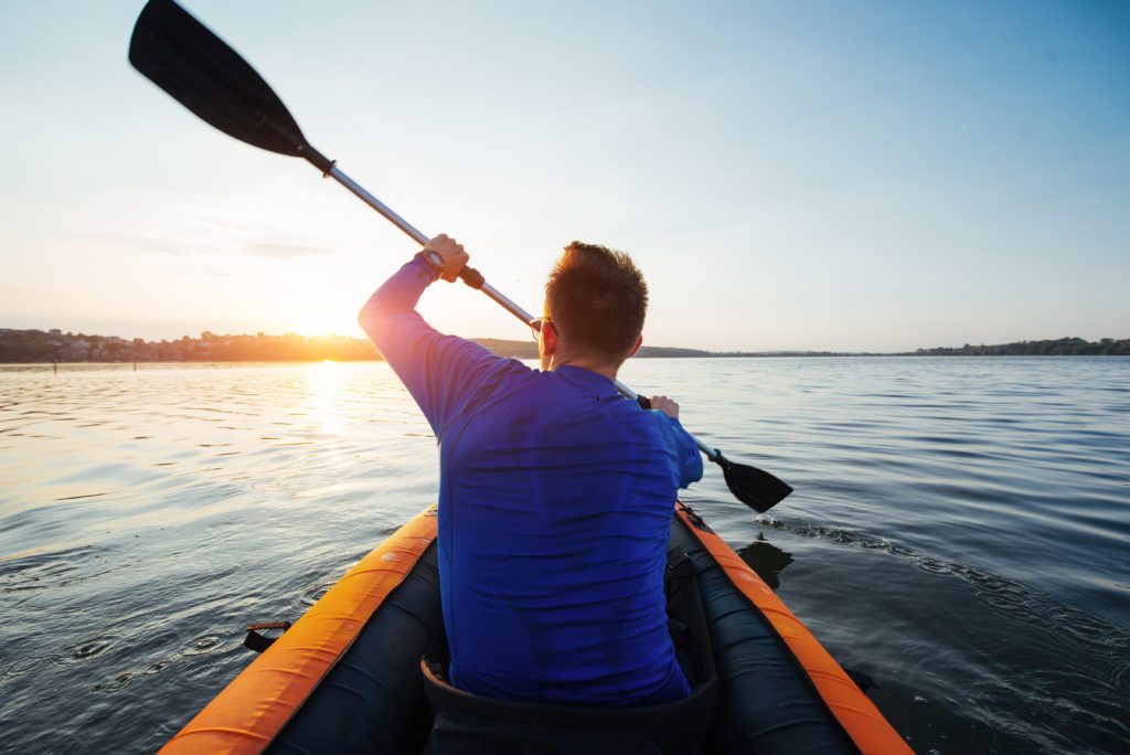 man floating on lake in a kayak at fantastic sunset
